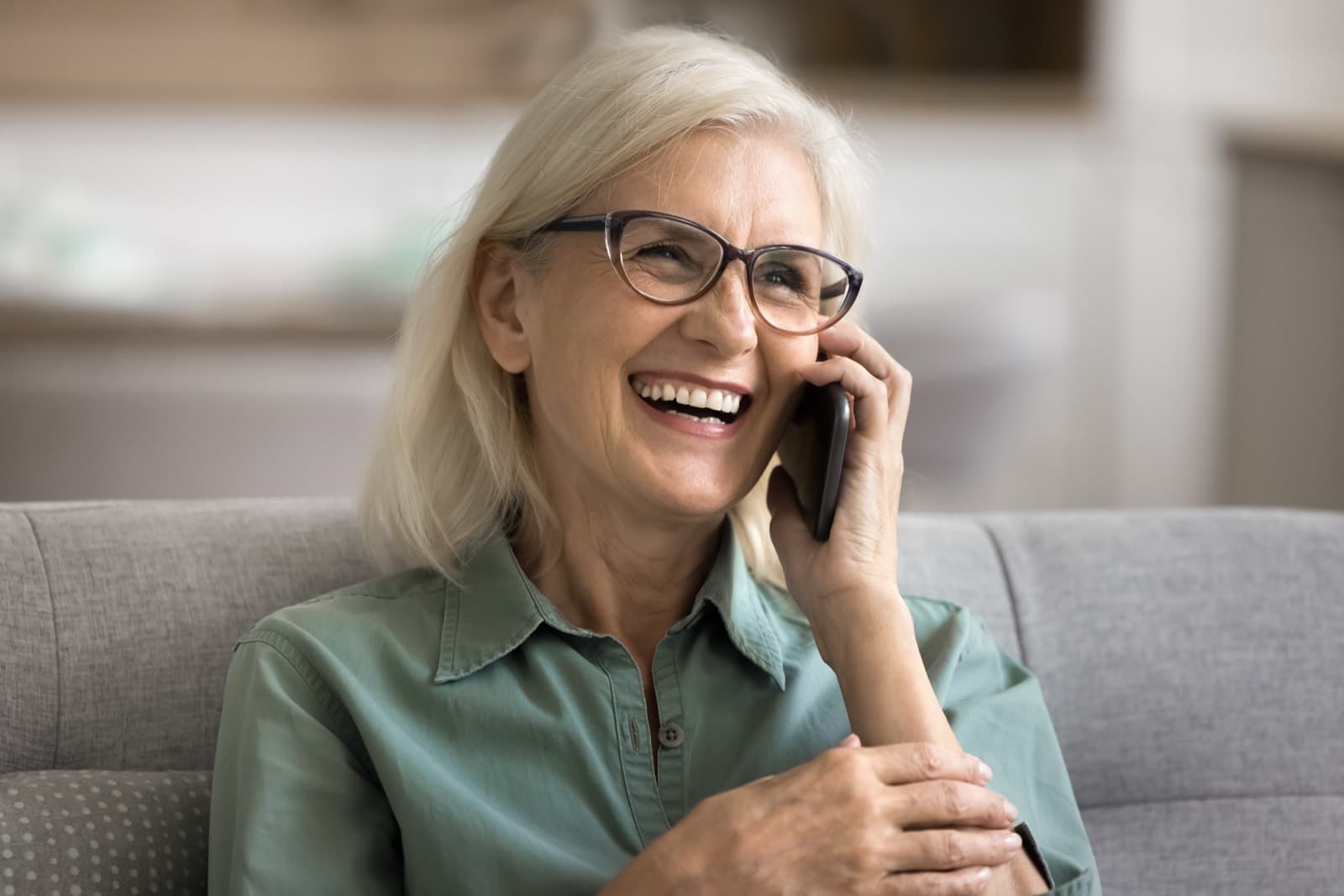 An older woman laughing during a phone call at home